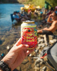 A hand holds up a drink can clad in the Rumpl Bevy Sack.