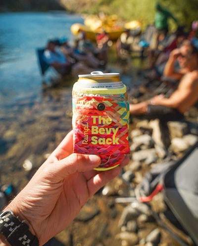 A hand holds up a drink can clad in the Rumpl Bevy Sack.