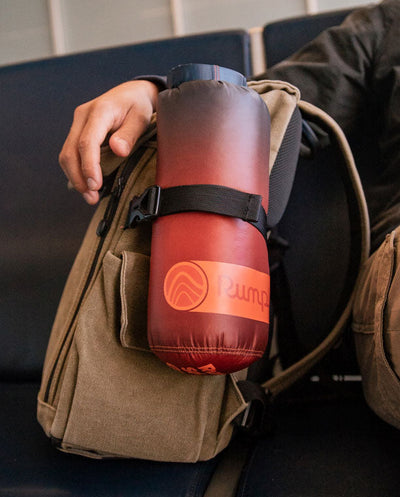 A Rumpl travel blanket attached to the side of a backpack.